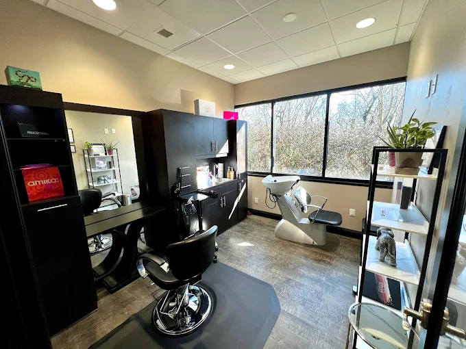 Inside Infinity Salon: a private styling suite with a styling chair, mirror station, and a window looking out to trees